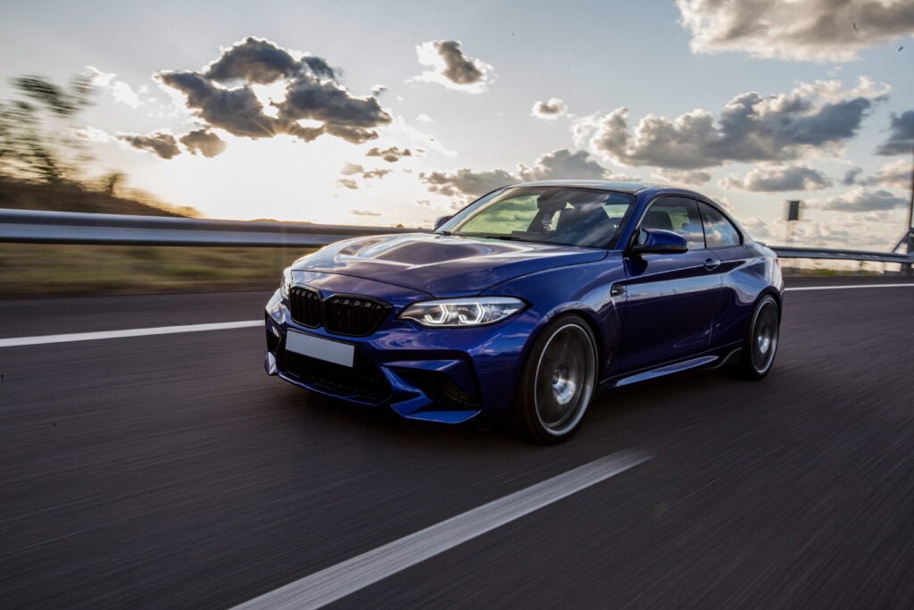 um carro azul sedan dirigindo na estrada em um tempo nublado