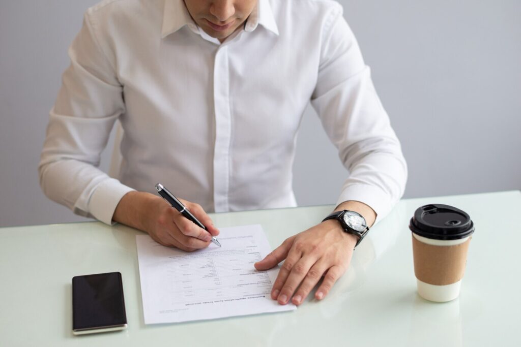 homem de negocios serio sentado a mesa e preenchimento de aplicativo 1262 17183
